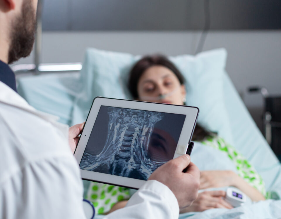 medic holding digital tablet with throat mri looking at sleeping patient in hospital bed e1700022743604